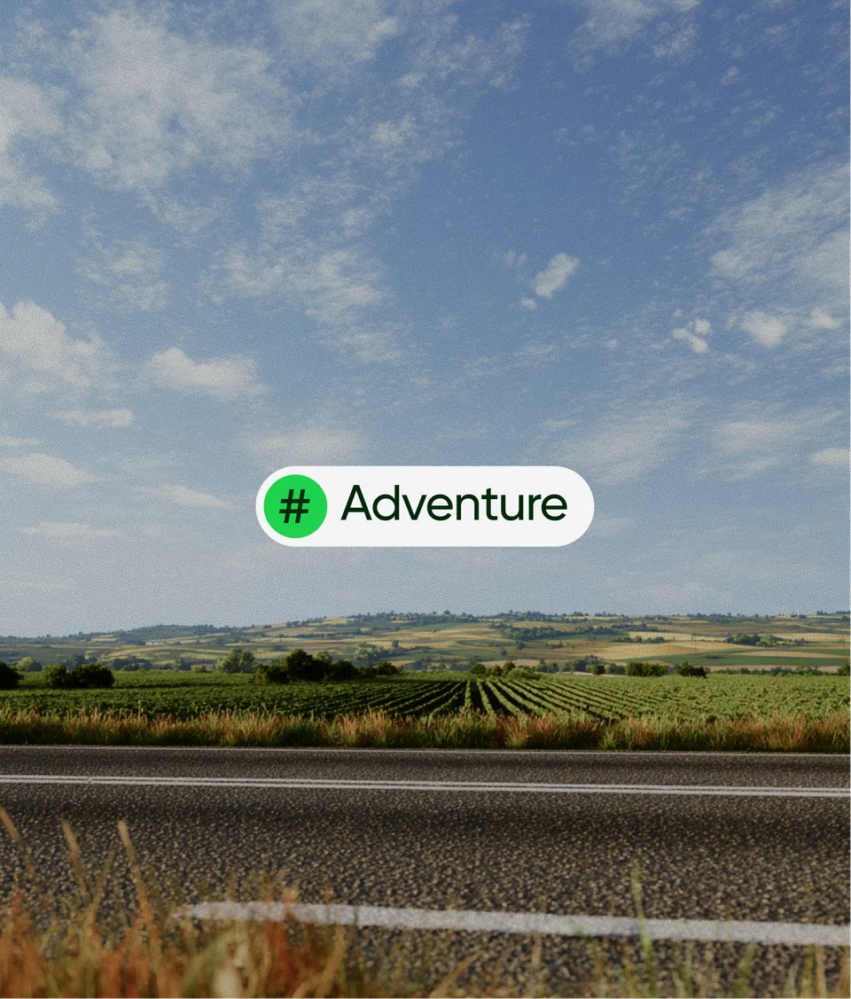 Adventure graphic with a green hashtag over a country road, fields and blue sky
